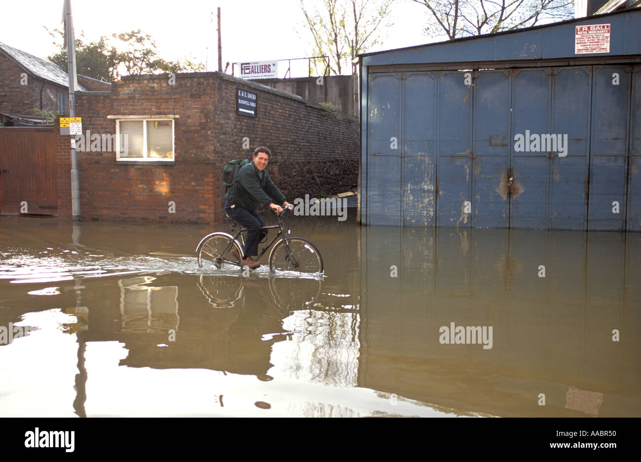 Cyclist rides through flooded road in Shewsbury Worcestershire after river severn floods the town Stock Photo