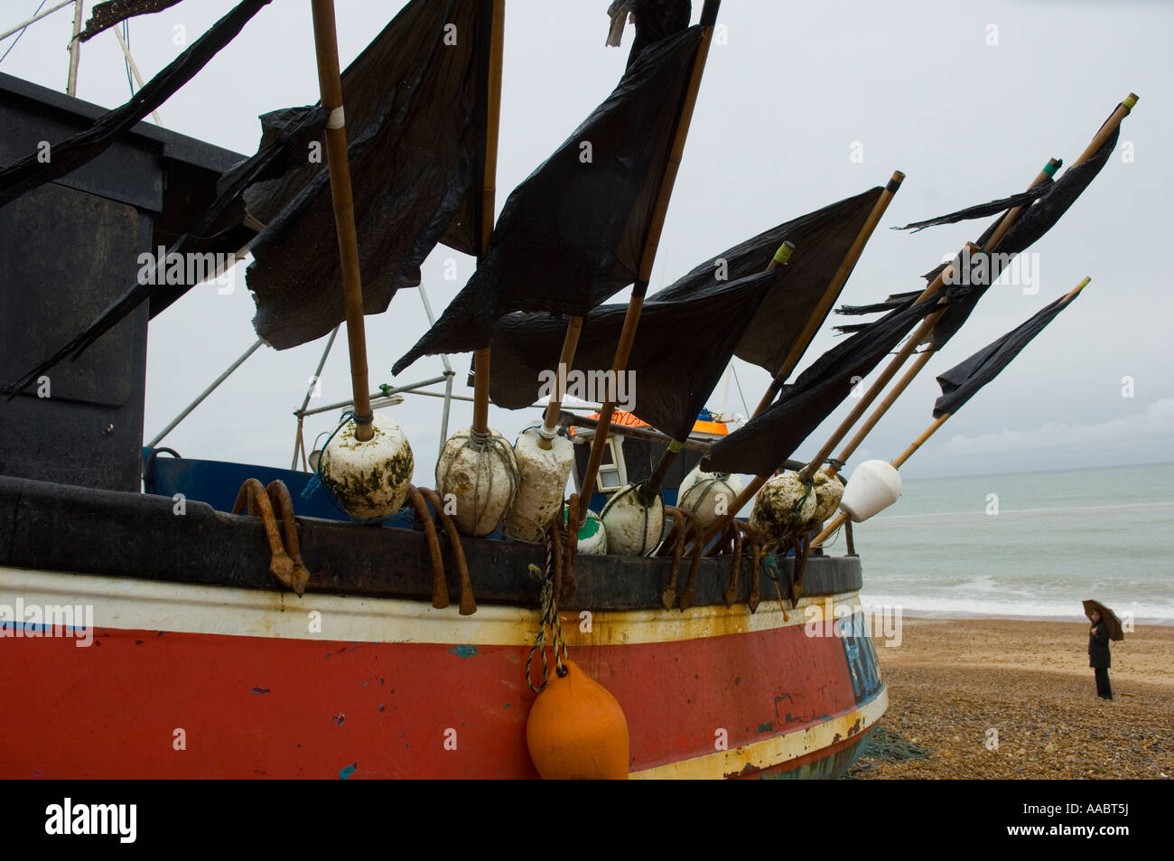 Fishing boat with black flags on the beach on a rainy day, Hastings Stock Photo