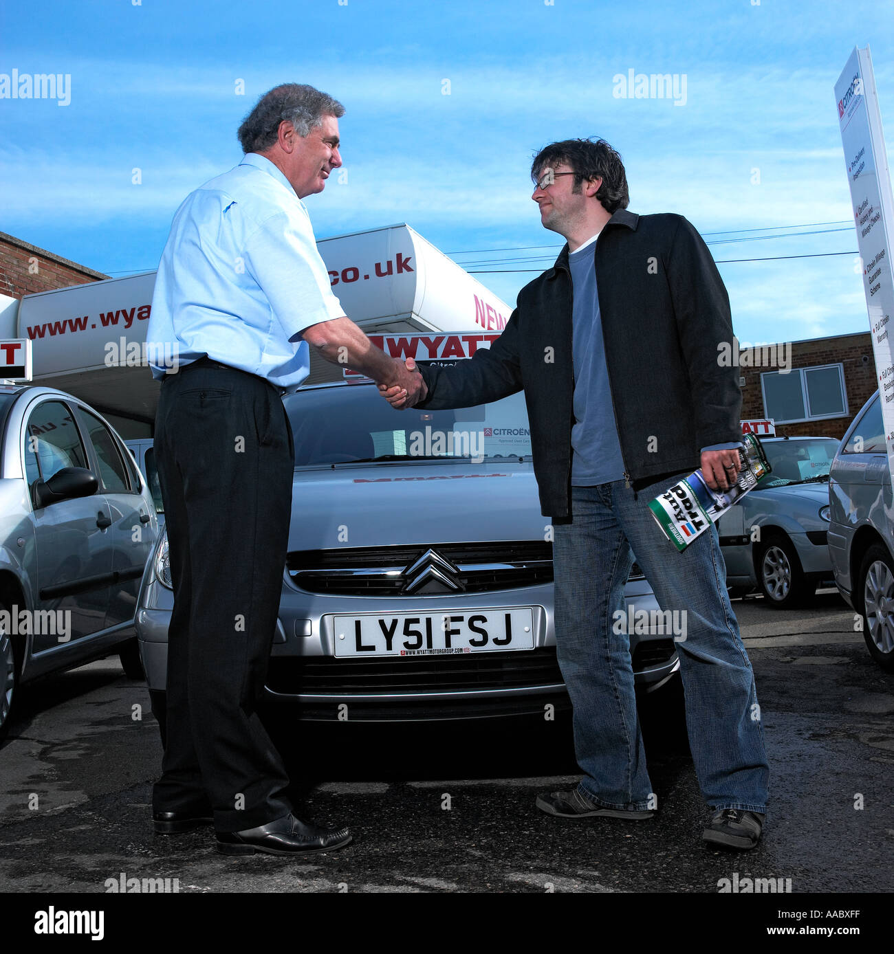 A car salesman shaking hands with a customer after clinching a sale Stock Photo