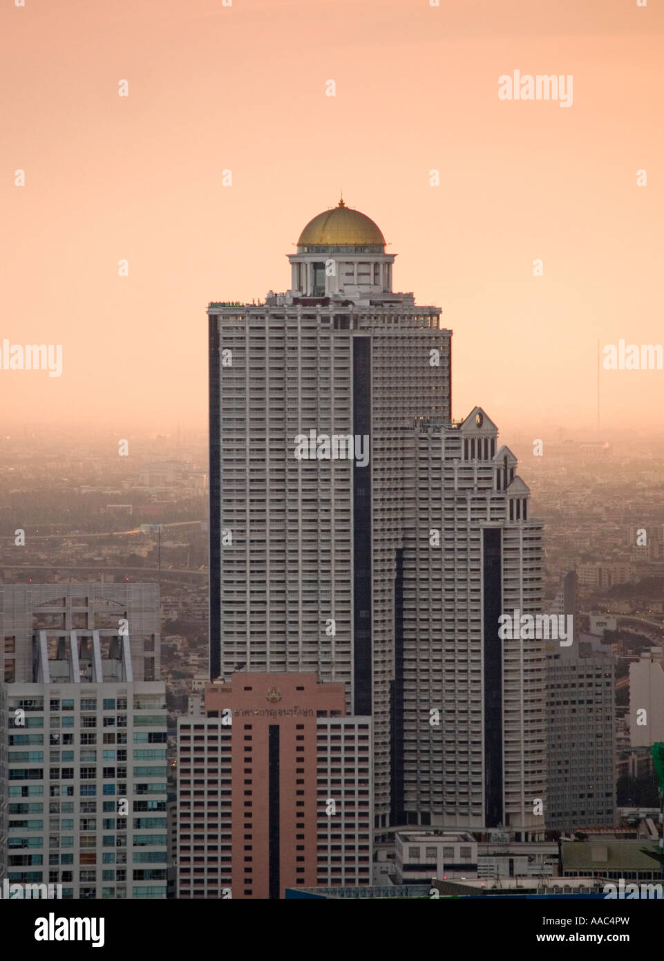 State Tower with Dome and Sirocco restaurant loom over a hazy Bangkok sunset Stock Photo