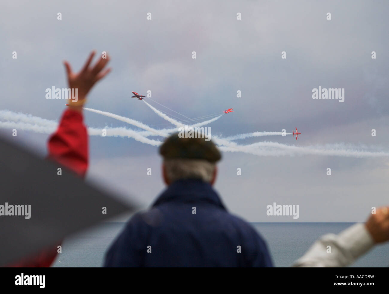 People watch Red Arrows flying display team one waving in excitement at Croyde Bay Devon England Stock Photo