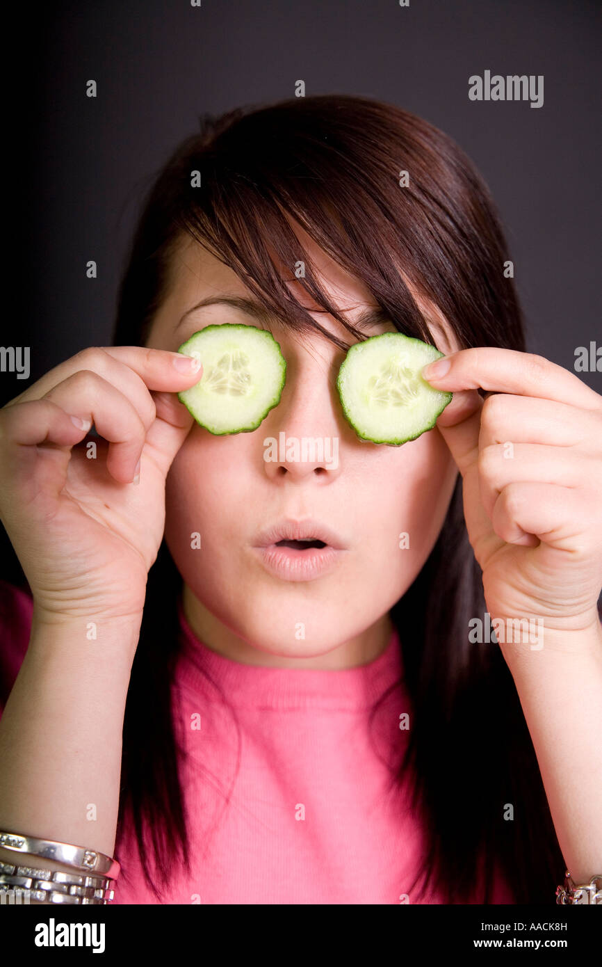Young girl aged seventeen with cucumber slices over her eyes looking