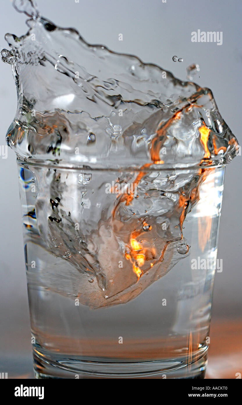 Ice cube falling into a glass of water Stock Photo - Alamy
