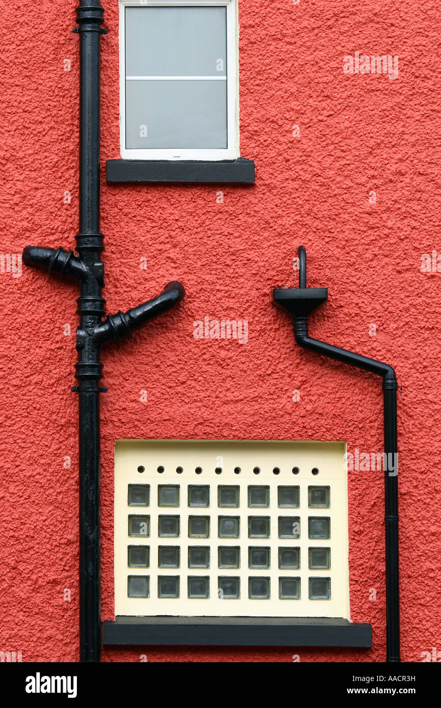 Window and black external drainpipe on a red house facade Stock Photo