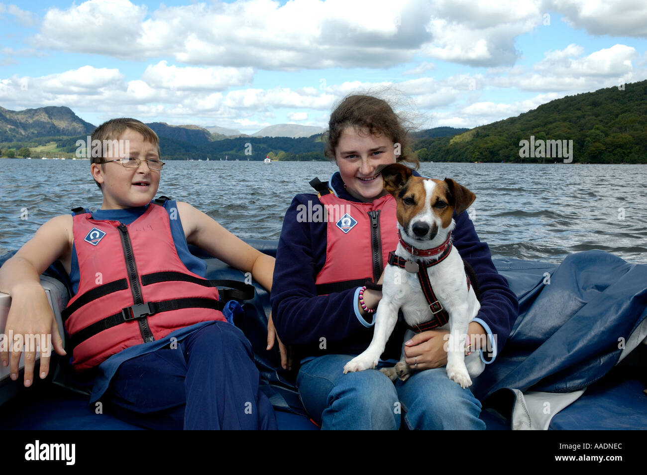 Brother and sister holding Jack Russell dog on electric boat on Coniston Water lake district