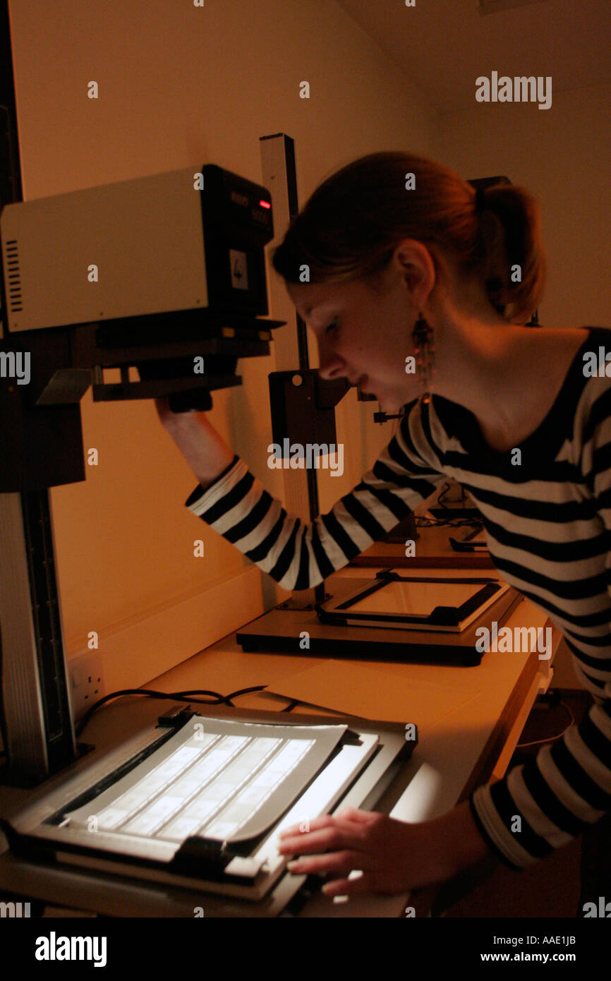 Female Student in photographic darkroom using an enlarger under a