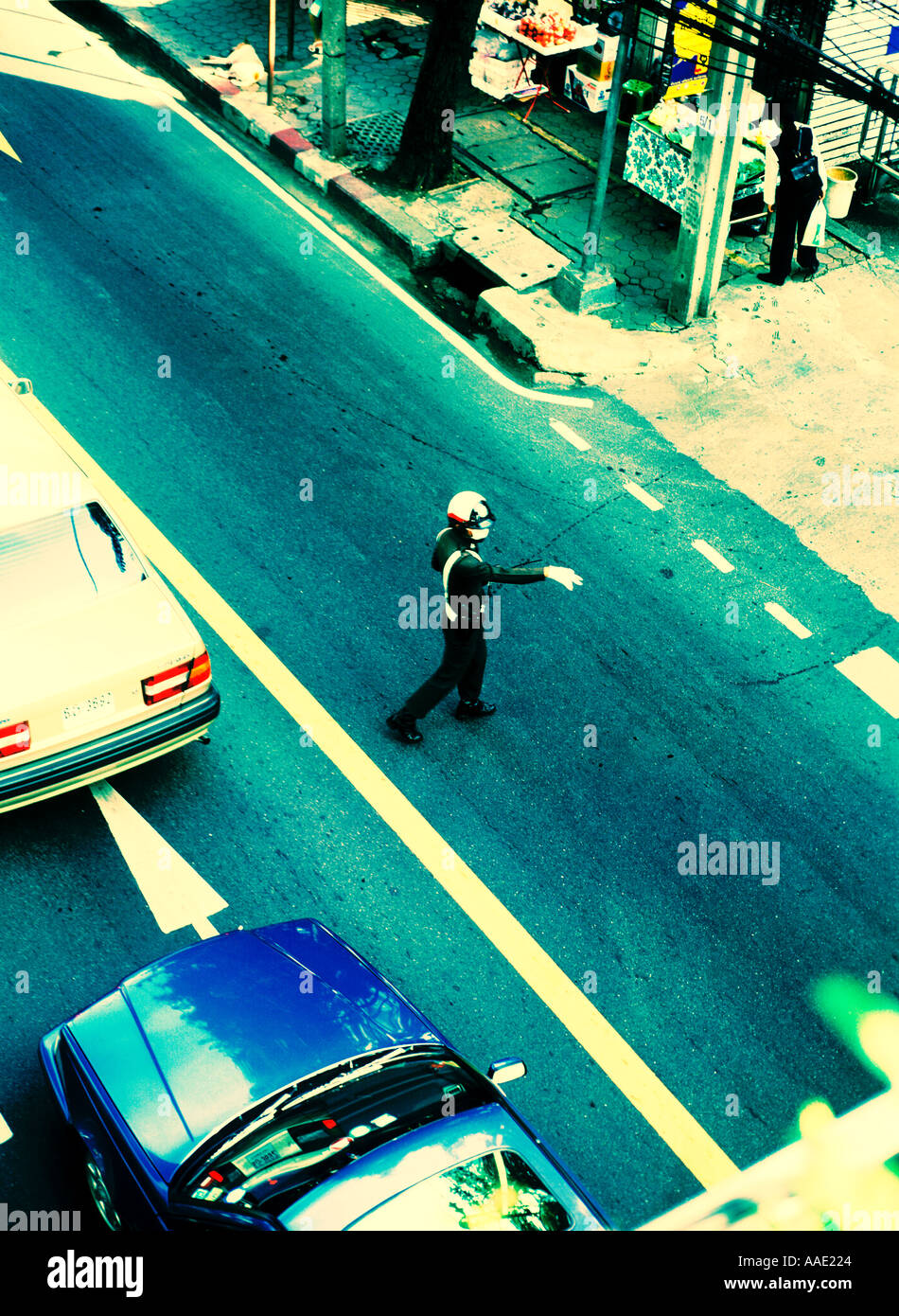 Thai policeman directing busy traffic along the popular Sukhumwit Road Bangkok Thailand as he points to motorists view from above and cross processed Stock Photo