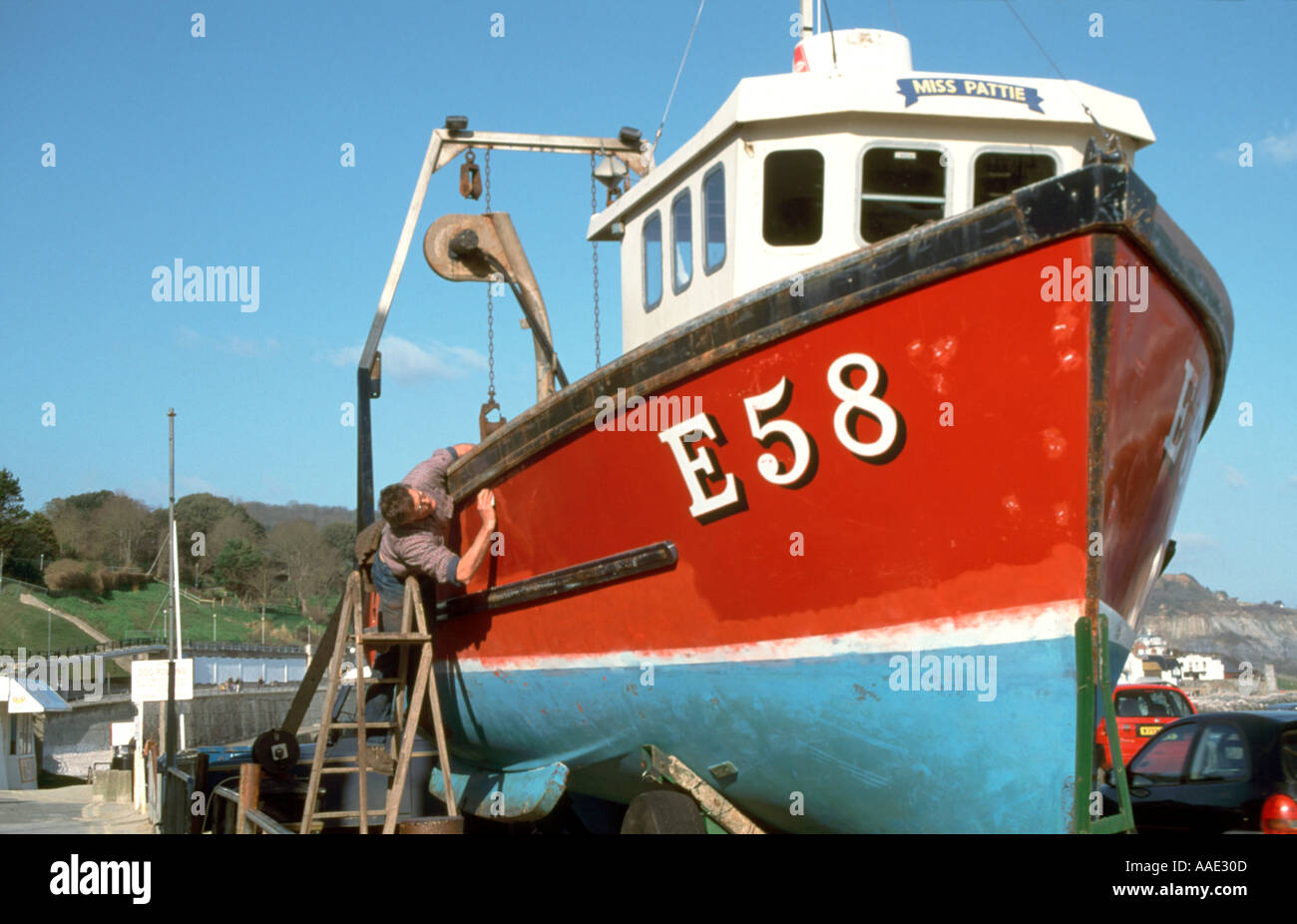 Man painting a fishing boat, Lyme Regis, Dorset, Wessex, England, UK