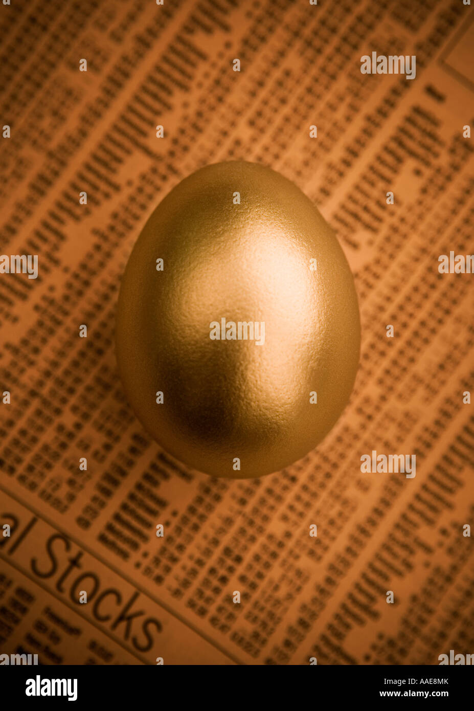 A studio shot of a golden egg on a stocks and shares print out. Stock Photo
