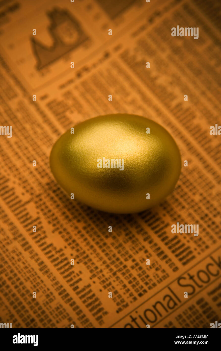 A studio shot of a golden egg on a stocks and shares print out. Stock Photo