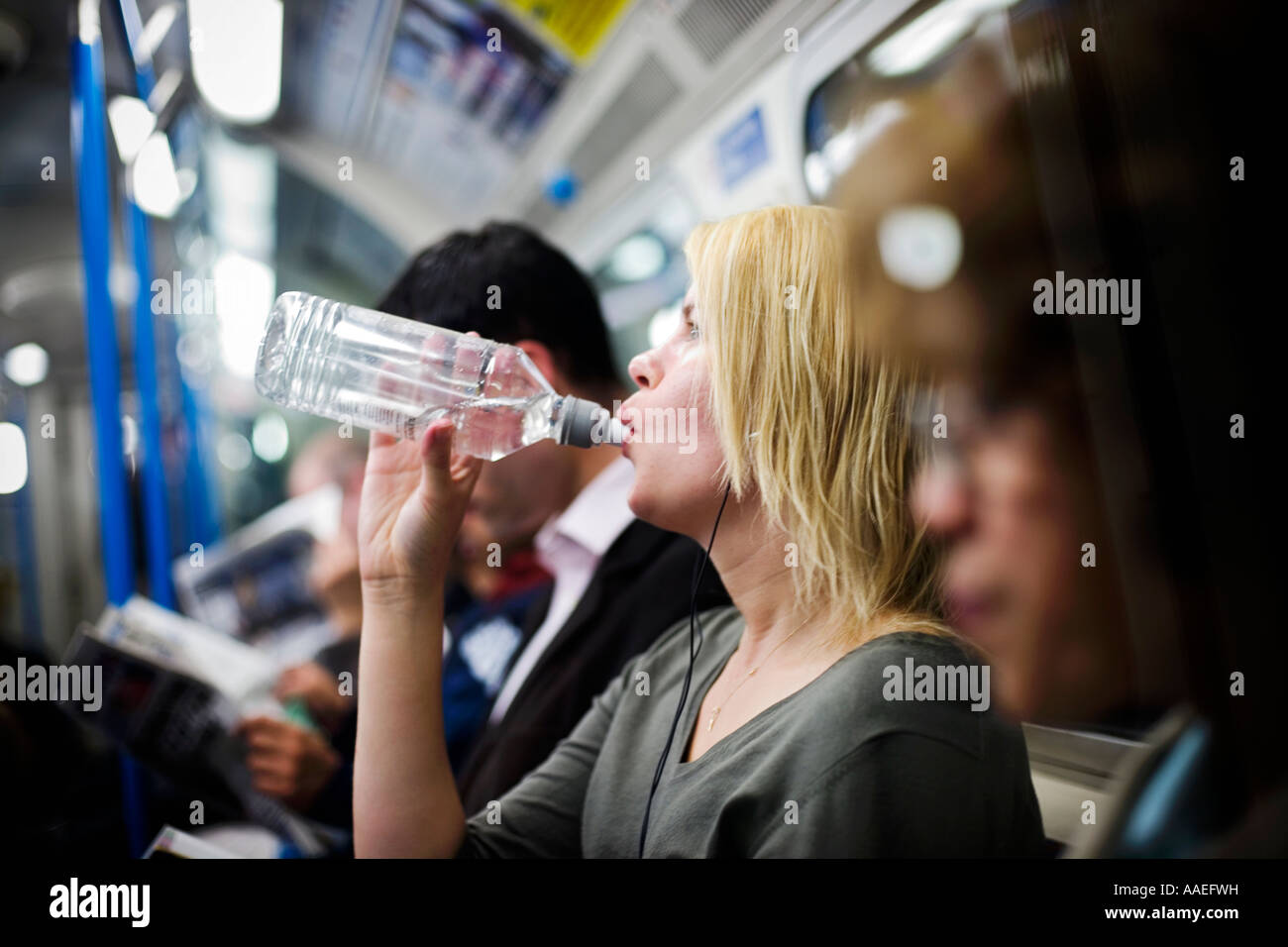Woman on tube train takes a drink of water during sweltering conditions Stock Photo