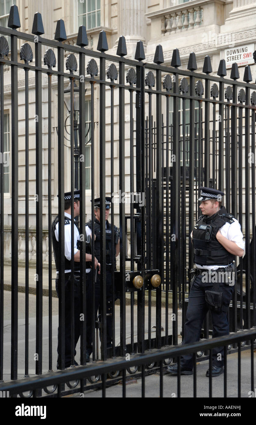Three uniformed police guards, two inside, and one outside main gates to Downing Street, London, England, UK Stock Photo