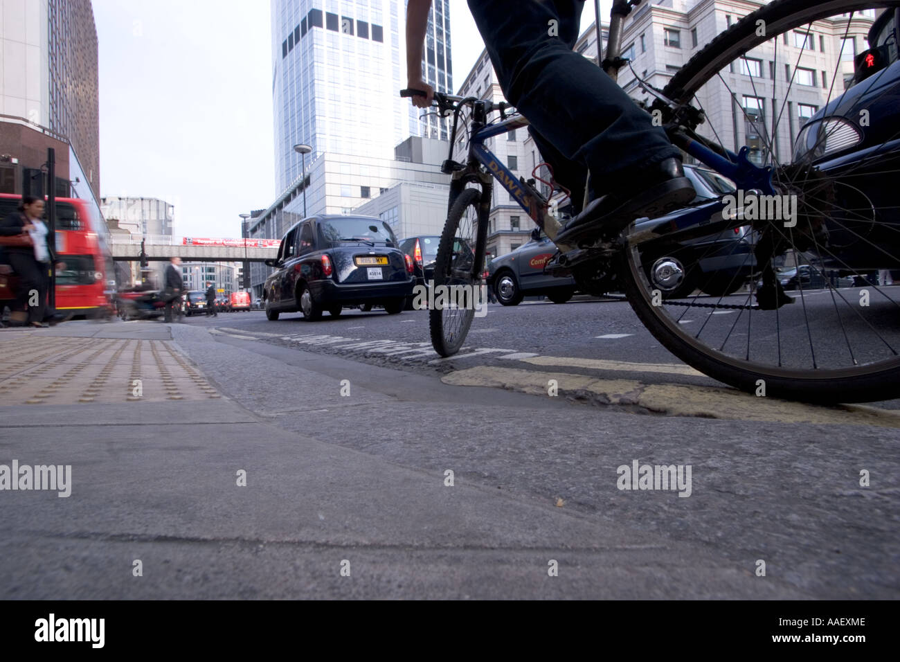 Low angle view of Cyclist riding on yellow line in Central London during evening rush with traffic Stock Photo