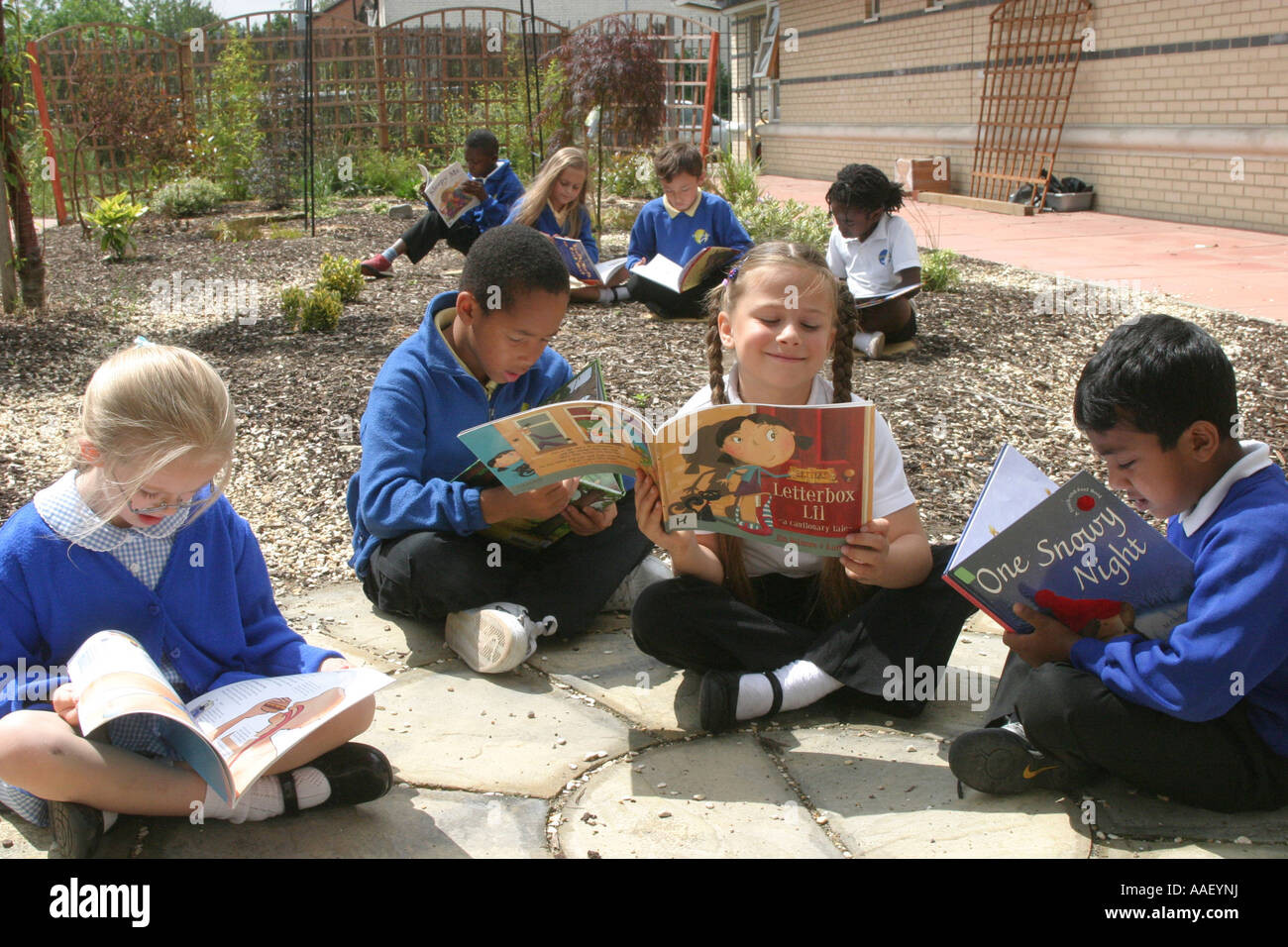 Primary school children in playground reading books Stock Photo