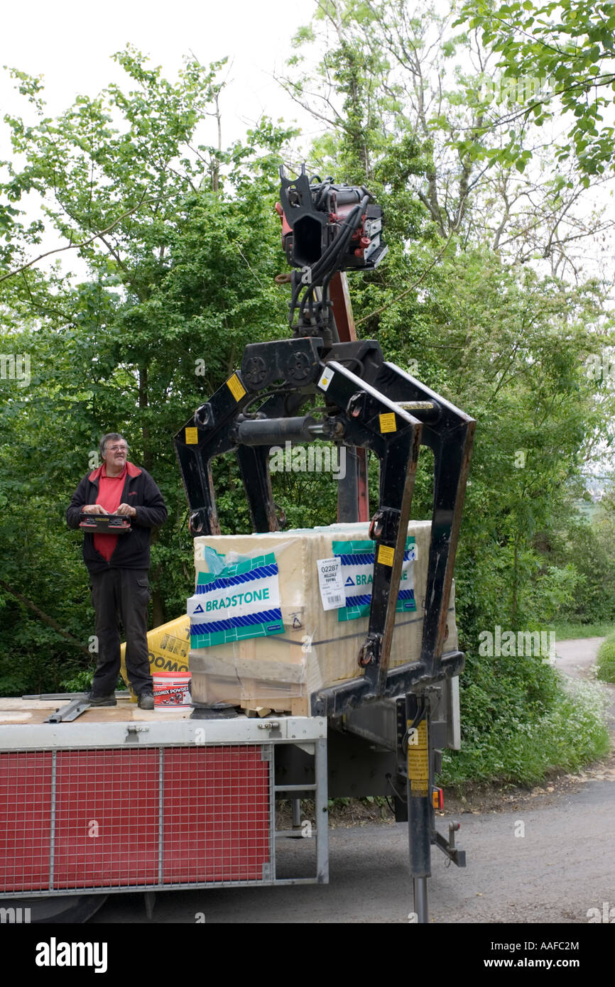 Truck driver using computer controlled pallet grabber to unload pallet