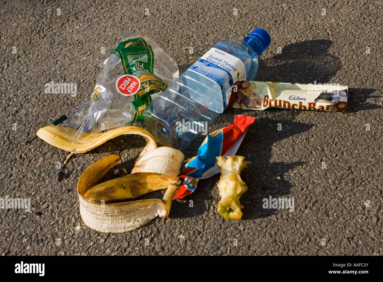 Discarded picnic litter and plastic packaging rubbish dumped on tarmac UK Stock Photo