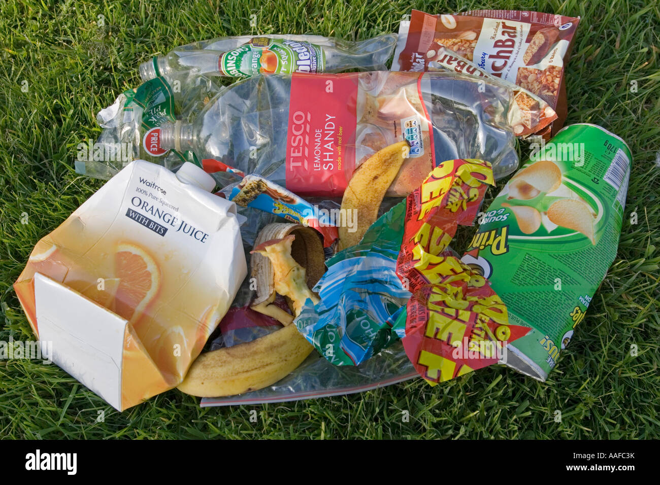 Discarded picnic litter and plastic packaging rubbish dumped on grass UK Stock Photo