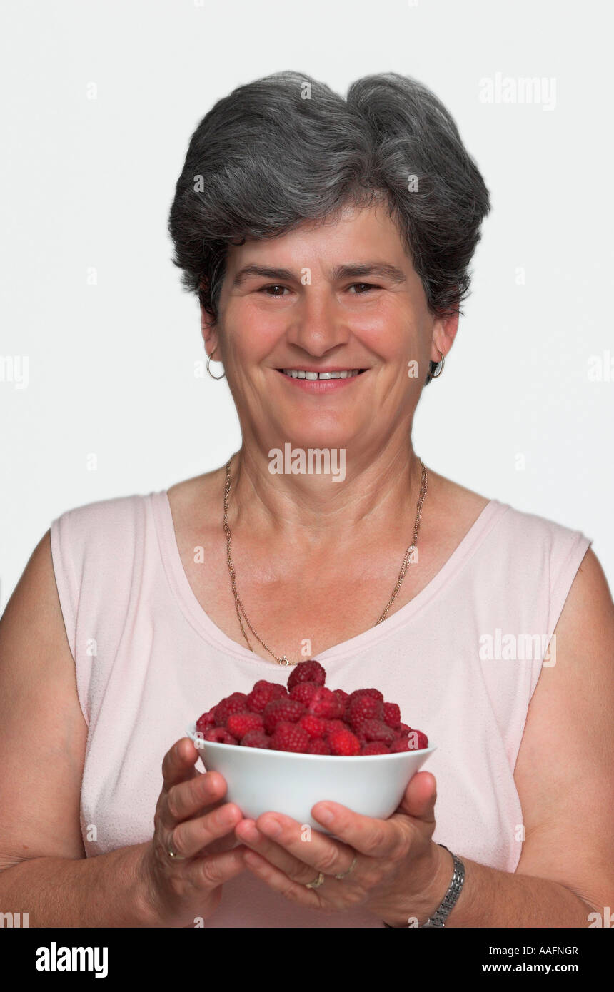 Mature woman holding bowl of raspberries portrait close up Stock Photo ...