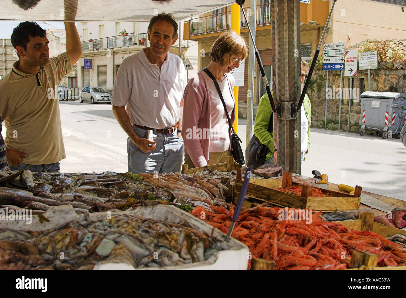 Buying fish at stall in market at Capo D'Orlando Sicily Italy Stock