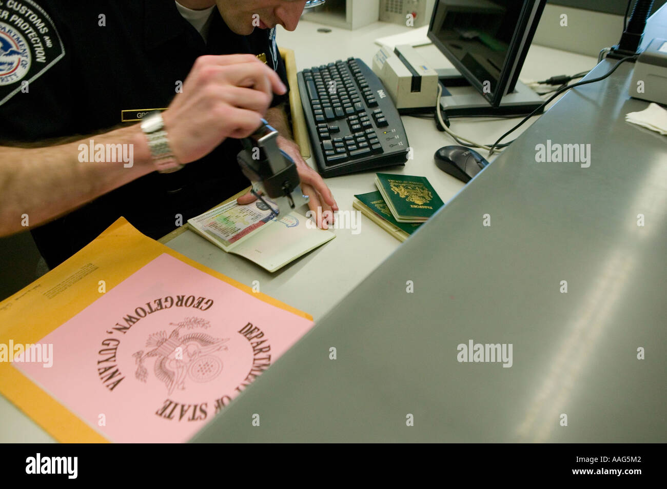 Customs and Border Protection officer in uniform stamps passport for arriving passenger at JFK airport, New York City April 2006 Stock Photo