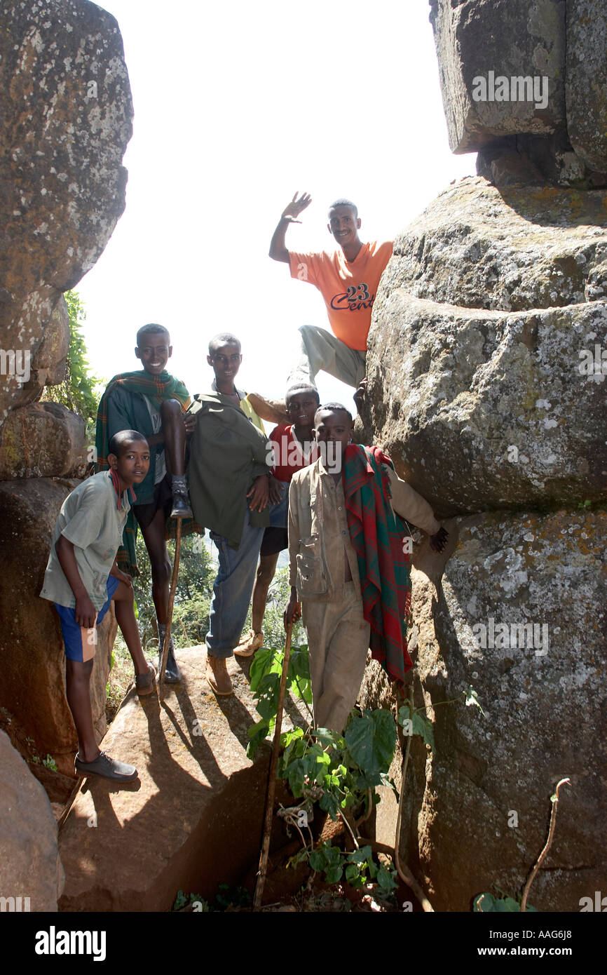 Young children playing posing standing on a stone between rocks with ...