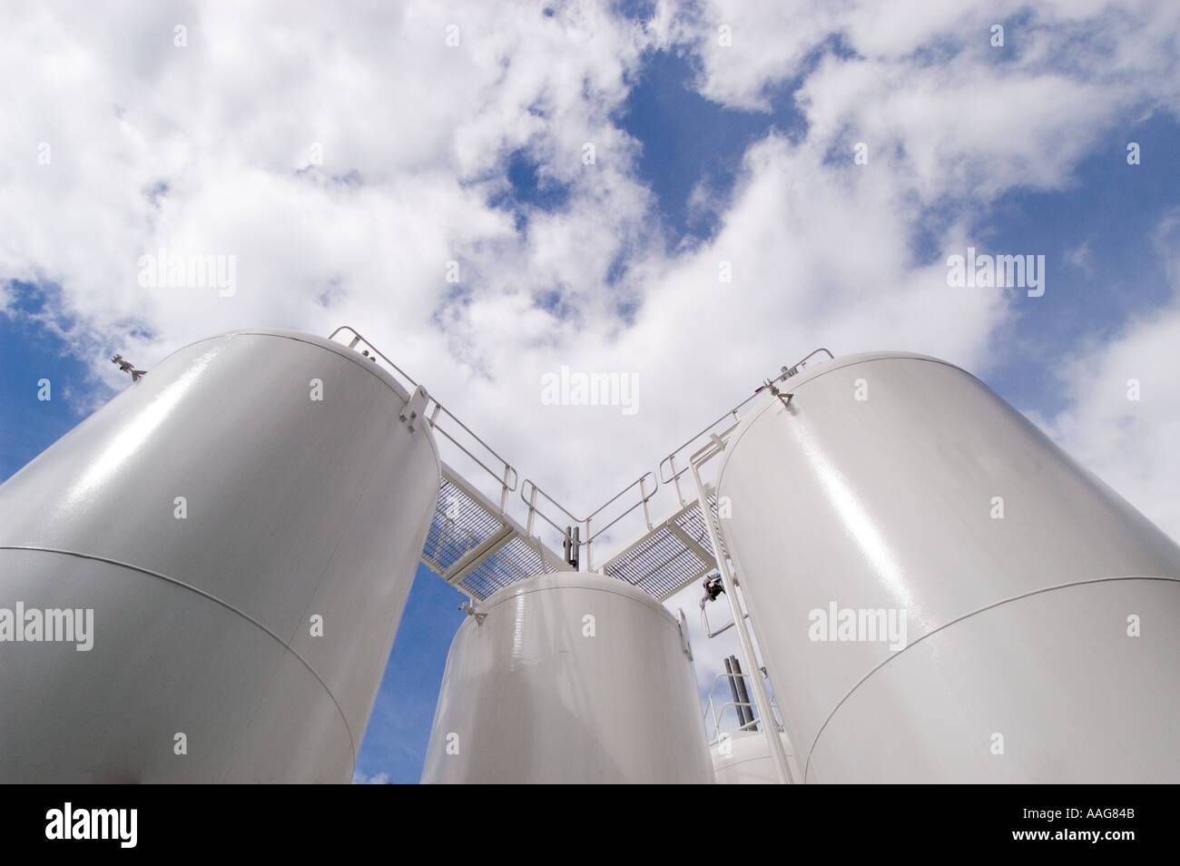 Storage Tanks seen against a blue sky with clouds Stock Photo - Alamy