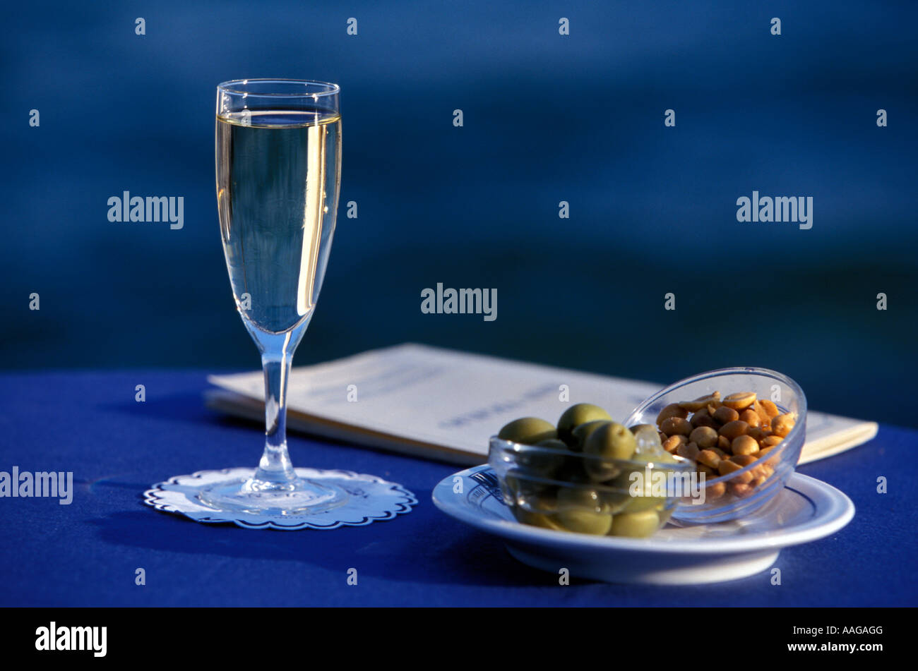 Glass of sparkling wine and dishes with olives and peanuts Punta San Vigilio lake Garda Veneto Italy Stock Photo