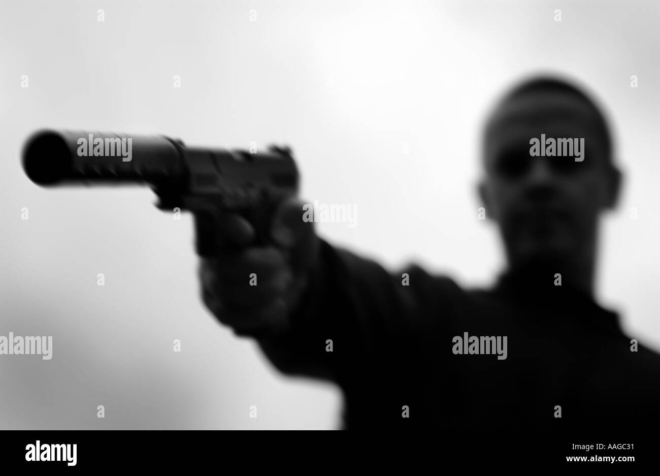 monochrome of a hitman with a silenced gun (Posed by model) Stock Photo