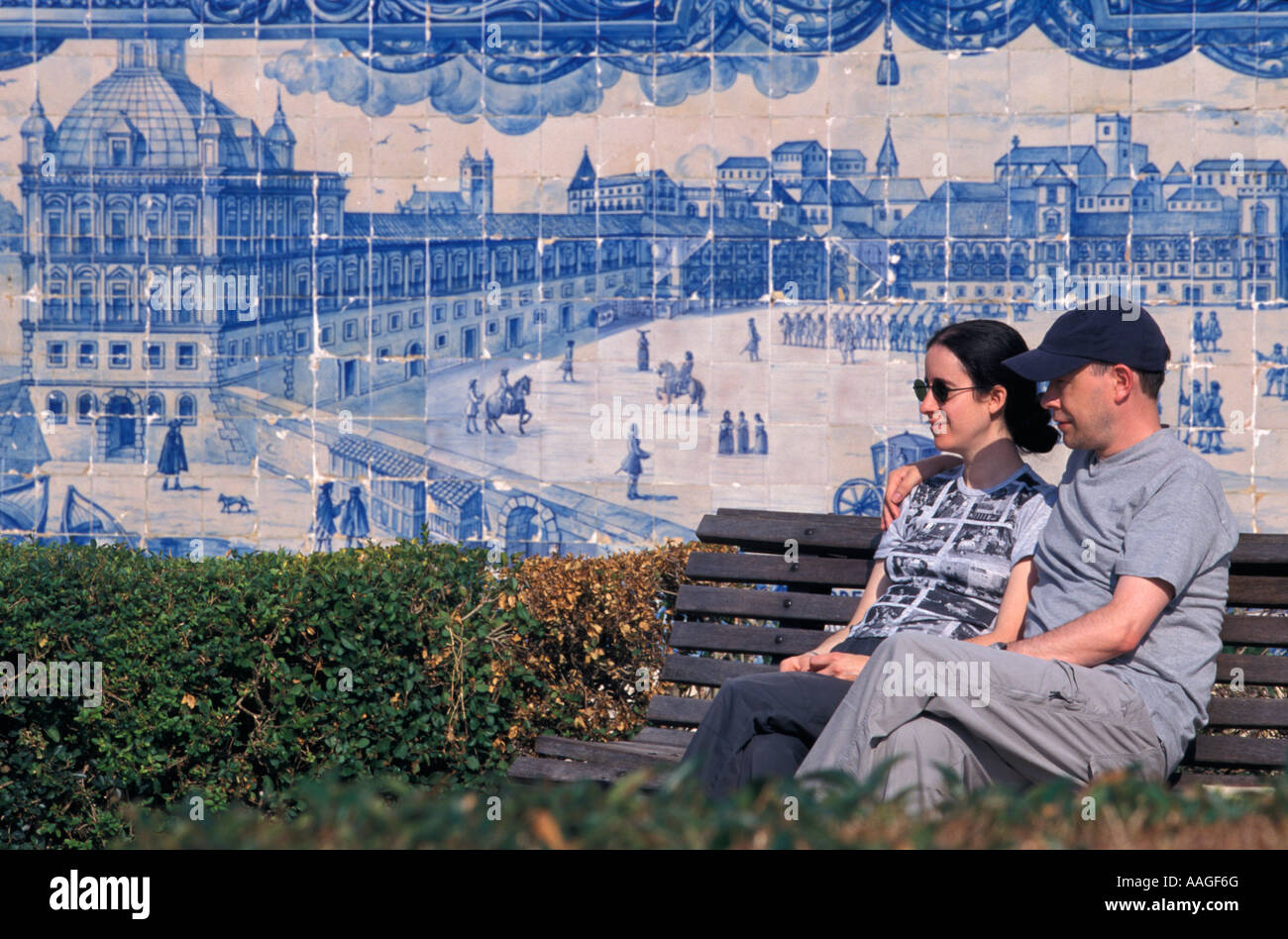 Couple sitting on bench in front of Azulejo wall Miradouro Santa Luzia Alfama Lisbon Lisbon Portugal Stock Photo