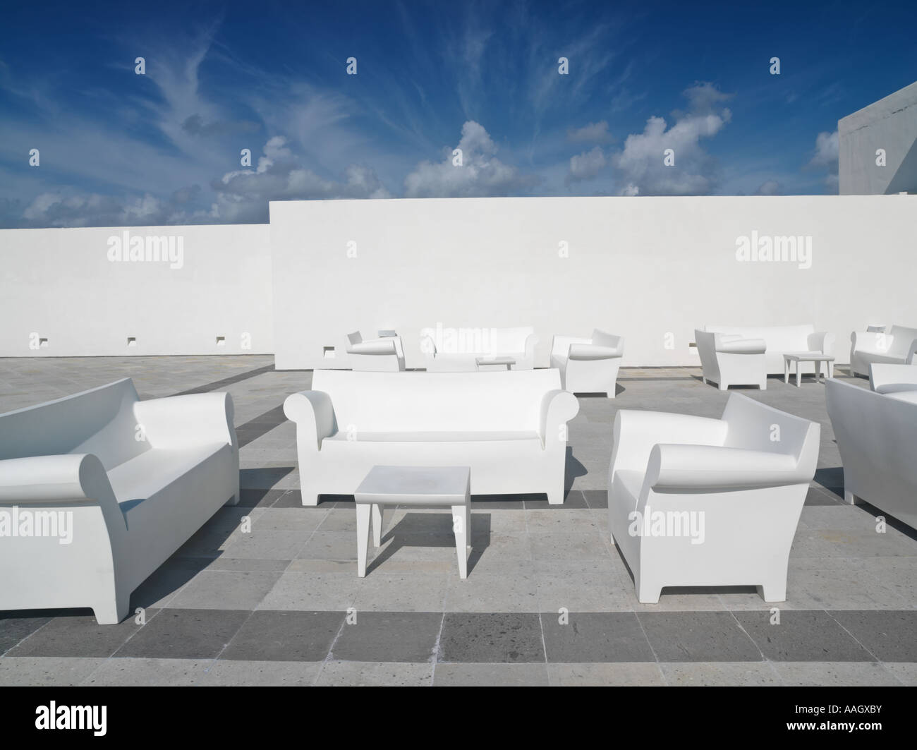 Mexico Quintana Roo Yucatan Akumal Mayan Riviera white chairs and couches against a white wall and blue sky in a surreal setting Stock Photo