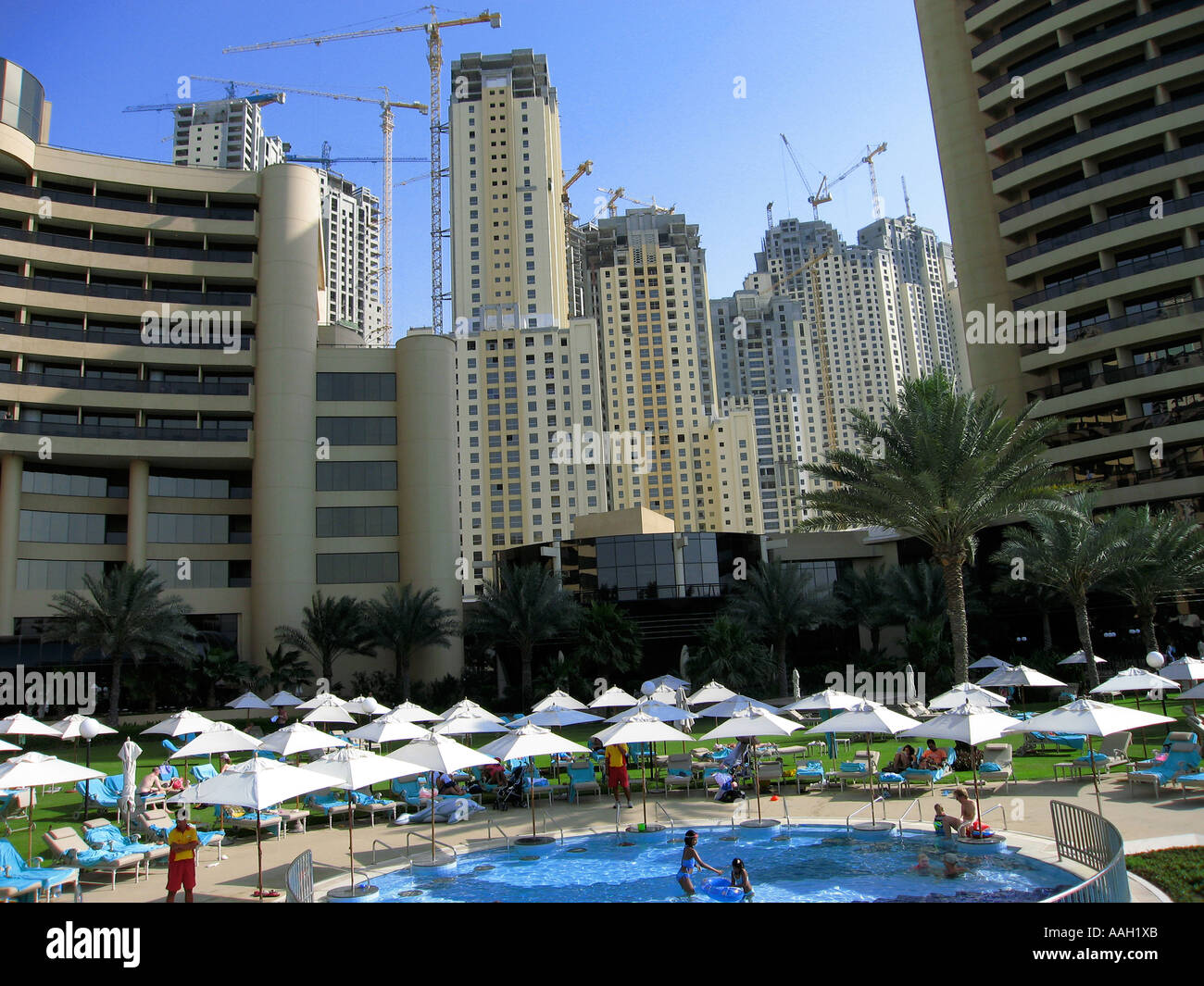 Construction of new high rise buildings in Jumeirah, Dubai, United Arab Emirates with hotel pool in foreground Stock Photo
