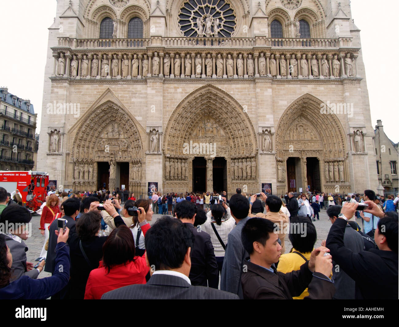 Crowd of japanese or chinese tourists doing Europe and taking pictures of the Notre Dame Cathedral in Paris France Stock Photo