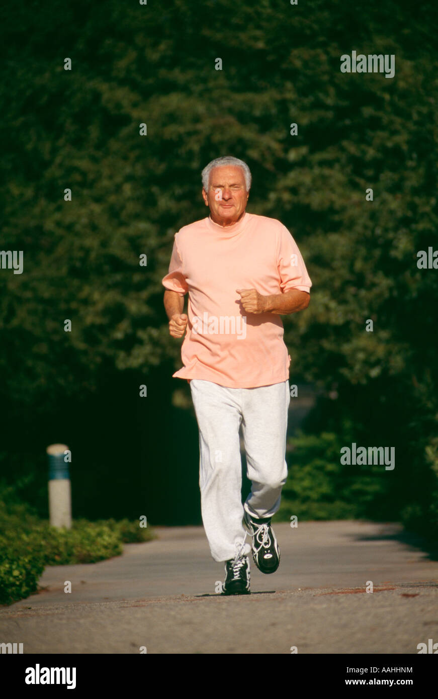 A smiling older man citizen male 73 year old running exercising exercise energy energetic in the park green copy space POV  MR Stock Photo