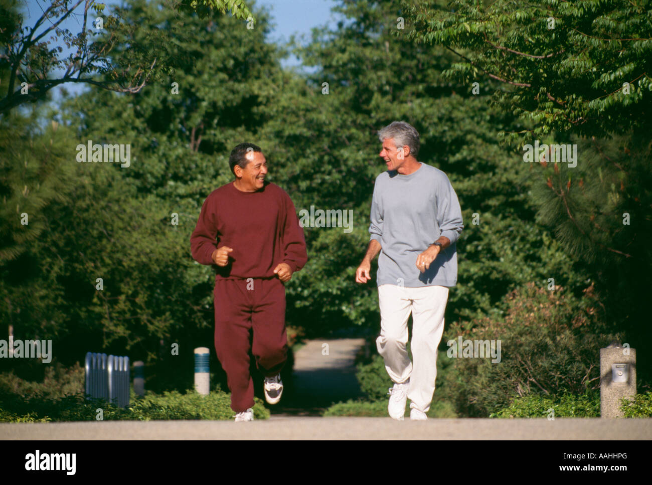 Senior men jogging along trail path ethnic diversity racially diverse African American caucasian, talking smiling Stock Photo