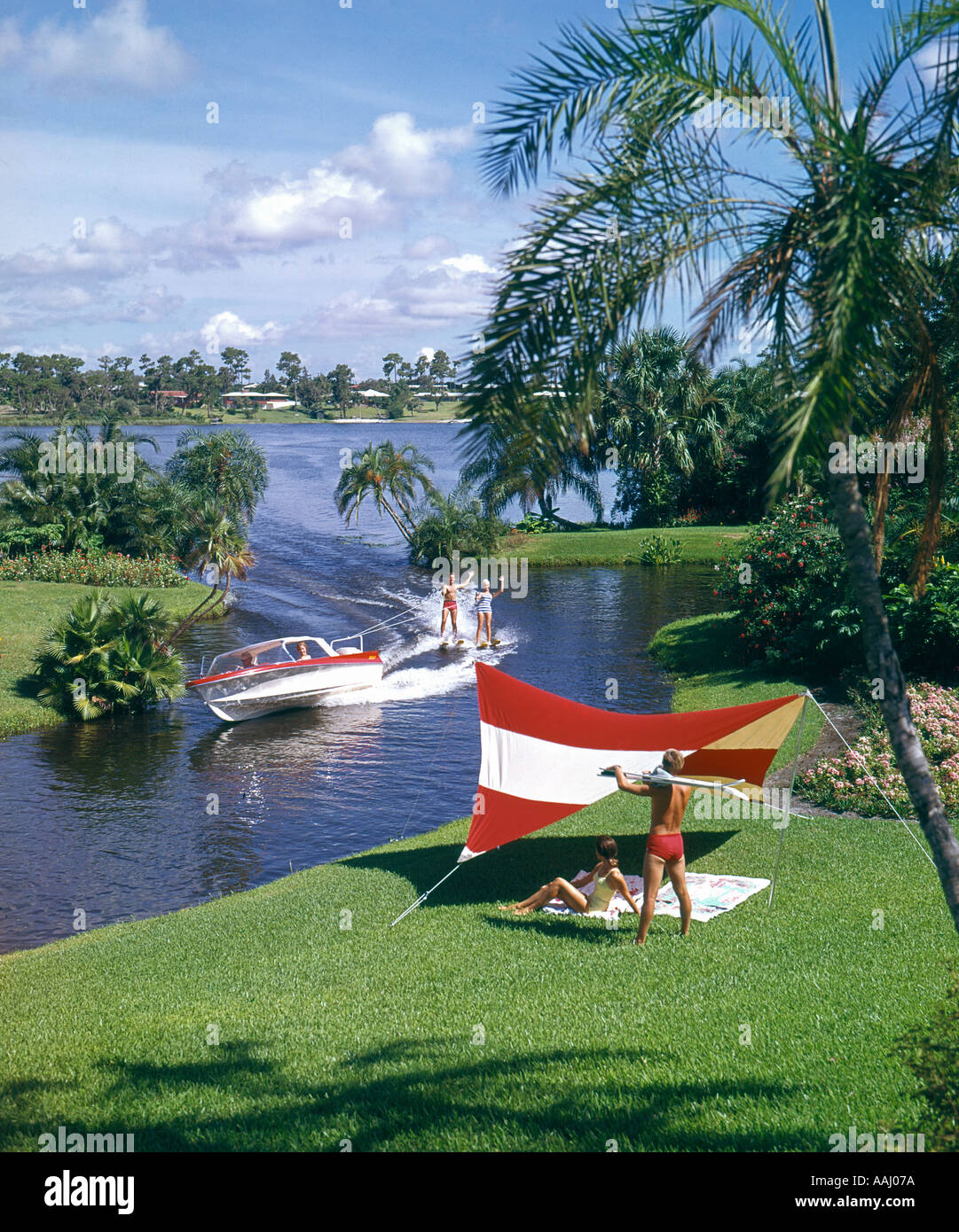 young adults water skiing speedboat through canal on Florida lake Stock
