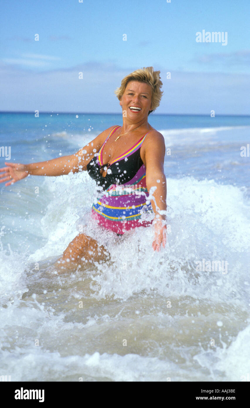 portrait of elderly woman running through water Stock Photo