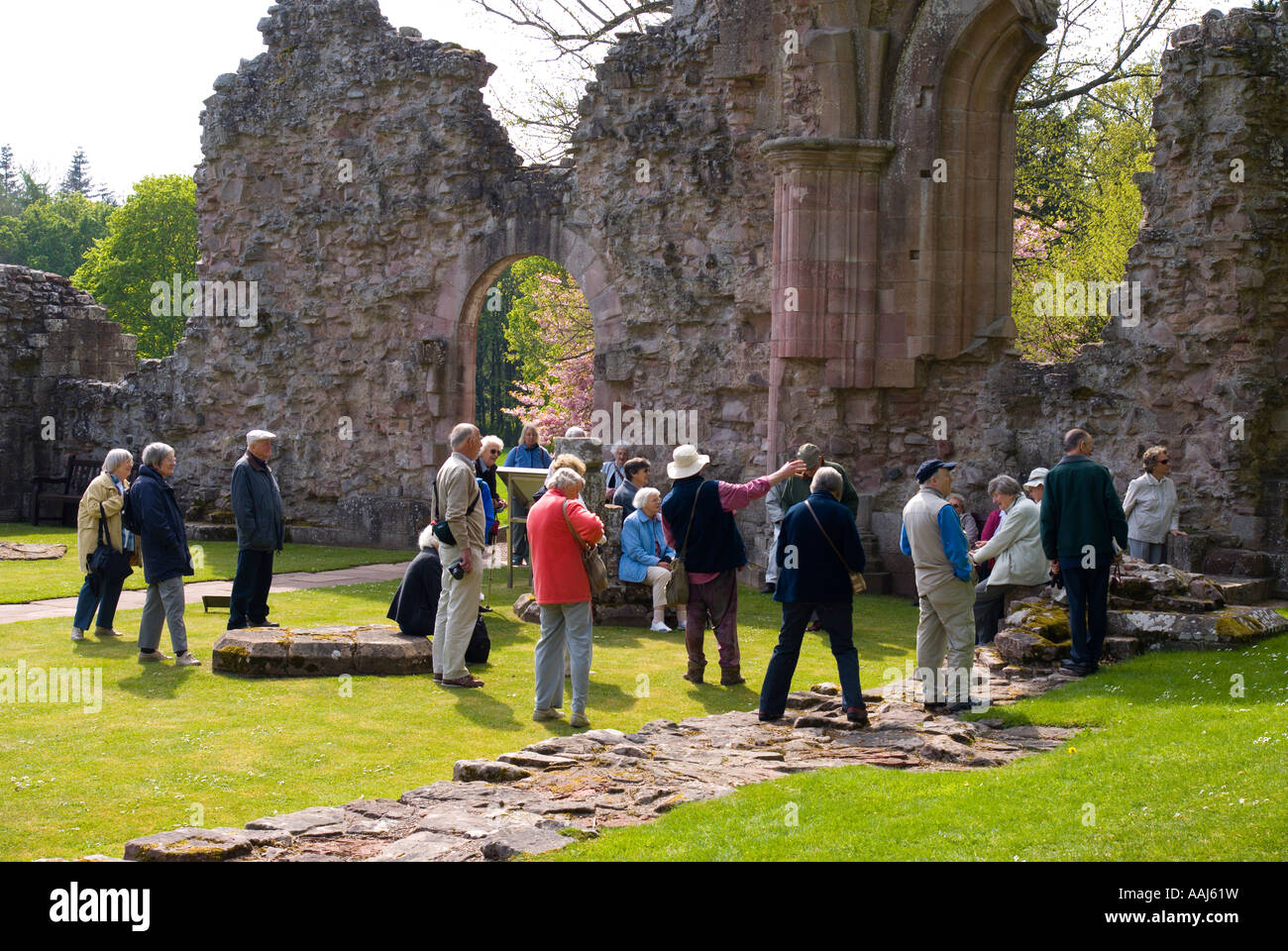 Coach tour party being shown Dryburgh Abbey in Scottish Borders UK Stock Photo