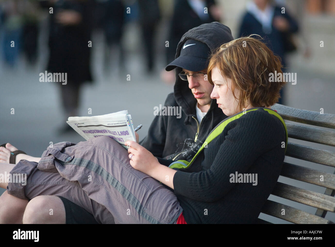 Young Couple Doing Crossword On Public Bench South Bank Of Thames