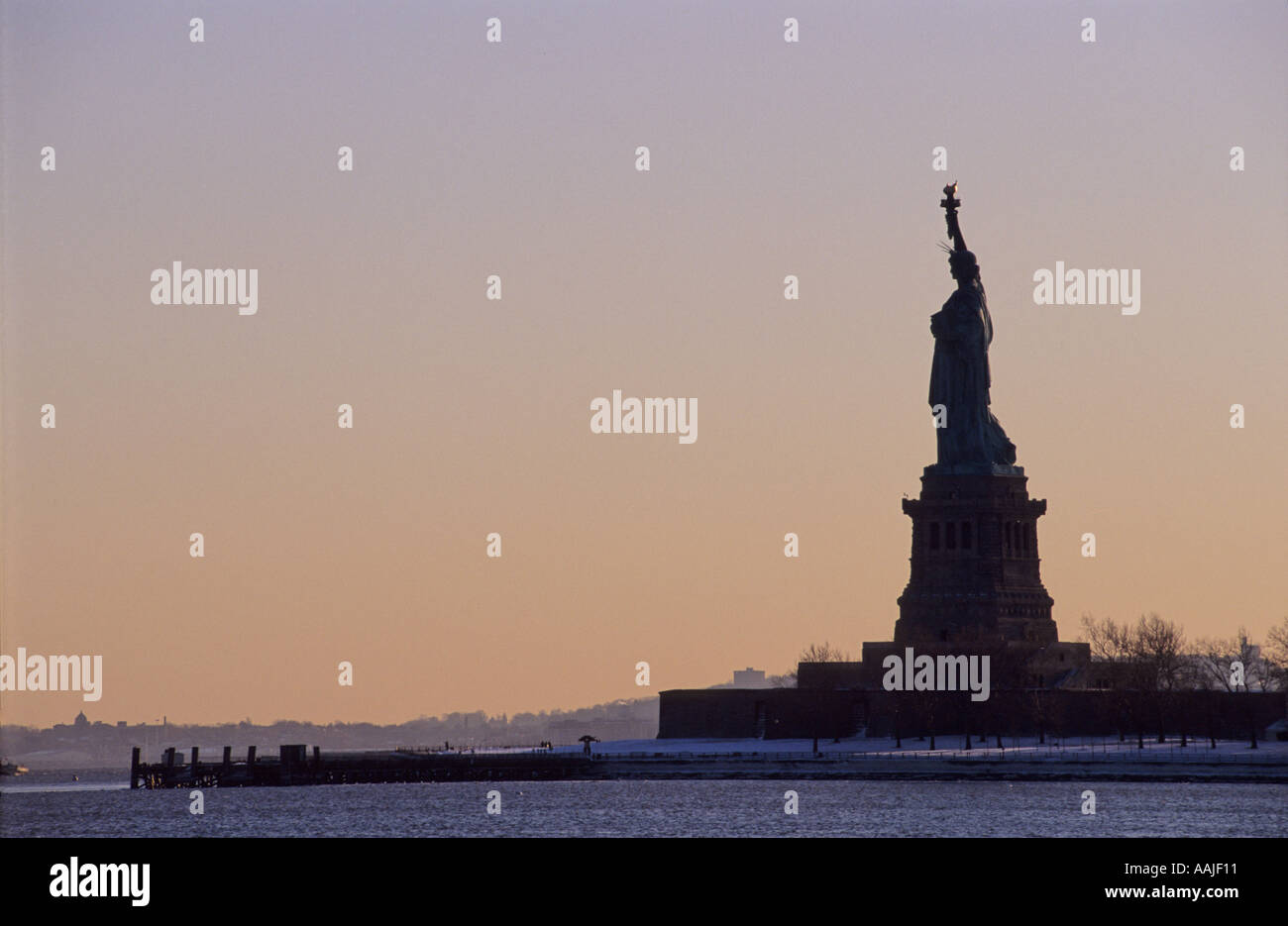 the statue of liberty in silhouette at sun set in profile New York City ...
