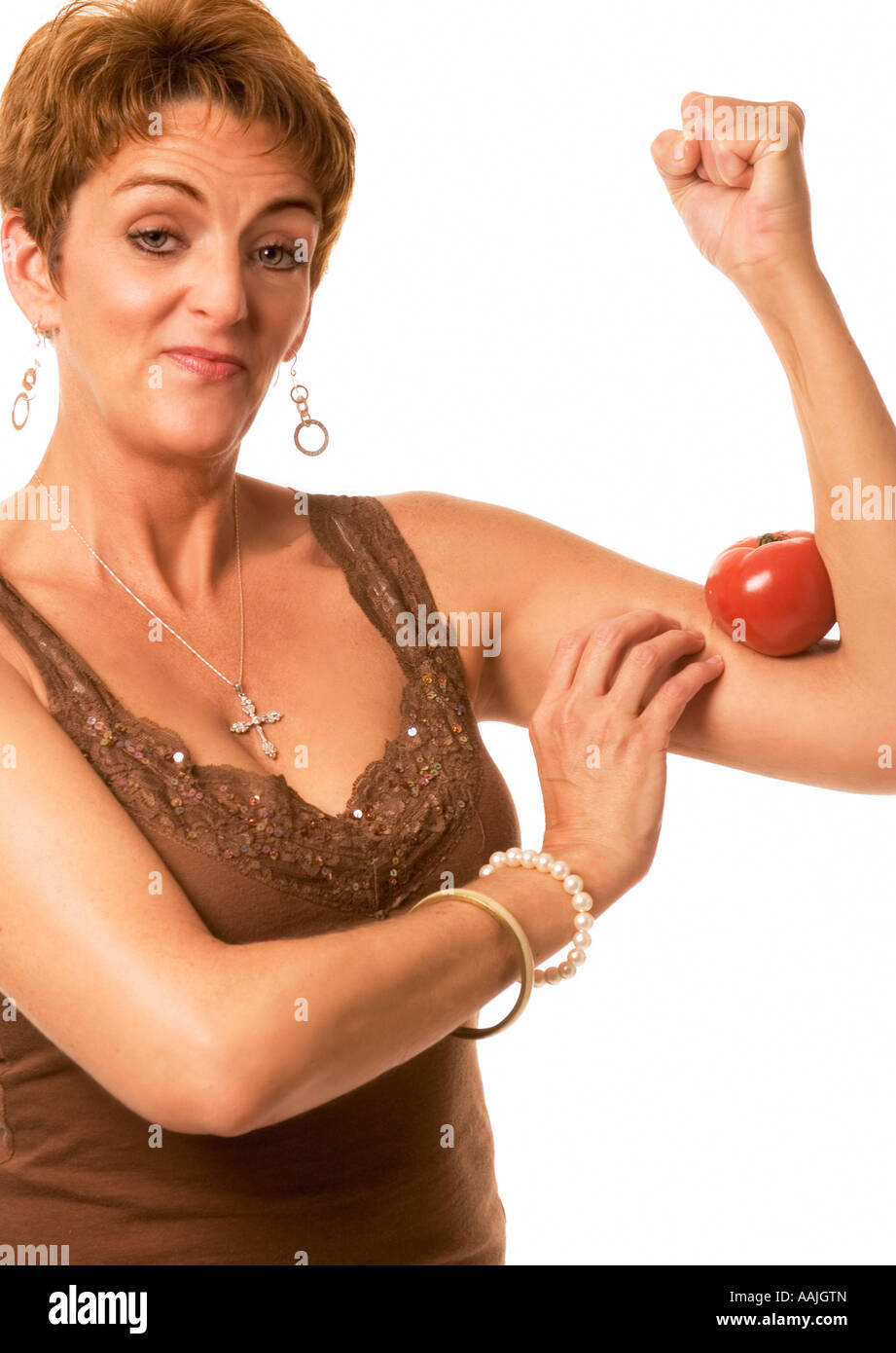 Closeup of Middle Aged Caucasian Woman (35-40) with Tomato Squeezed in Arm Muscle, Strength and Healthy Lifestyle Stock Photo