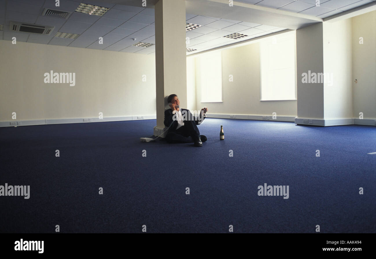 Young businessman in empty office space celebrating with Champagne Stock Photo