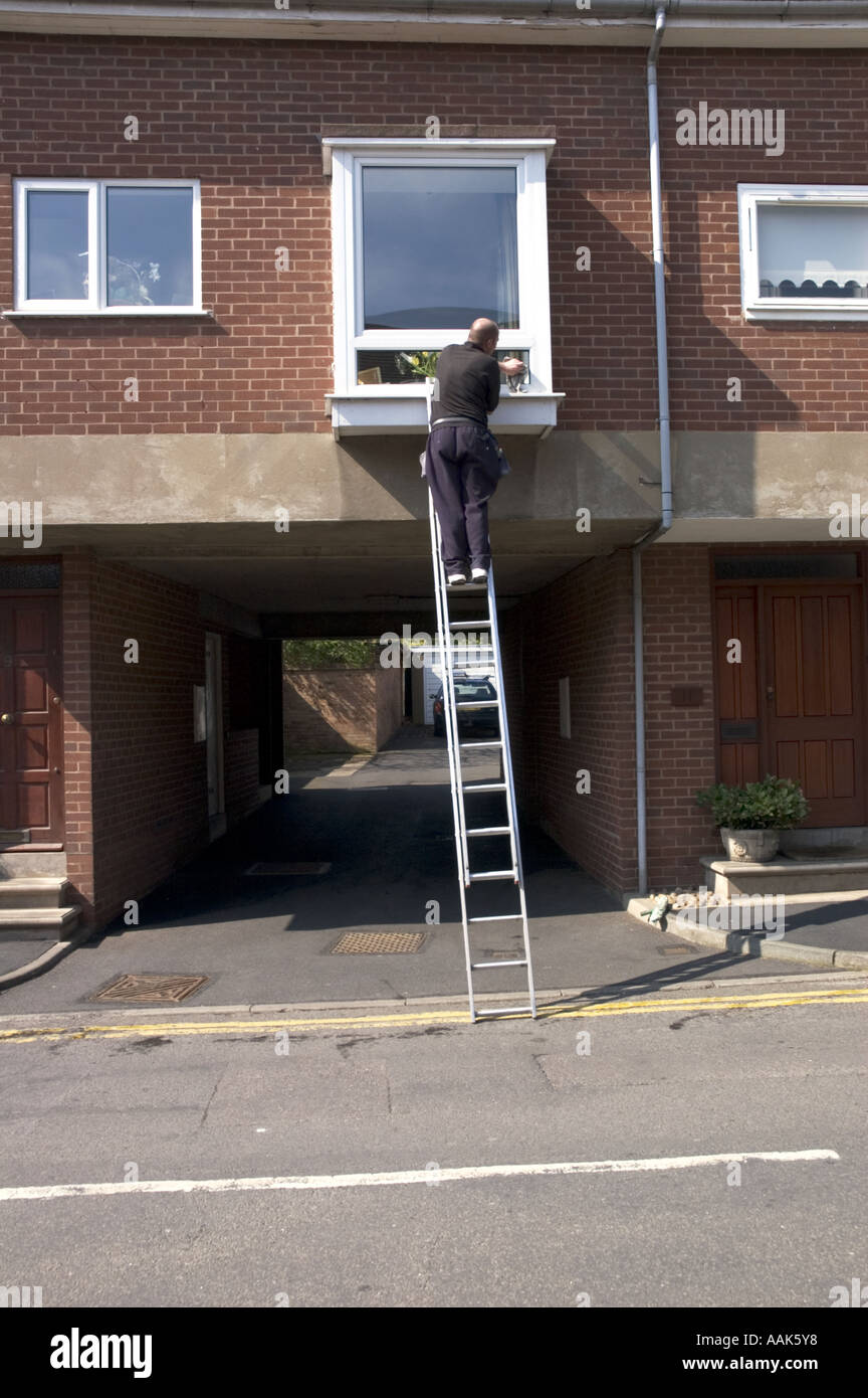 Window cleaner cleaning windows from a ladder Stock Photo Alamy