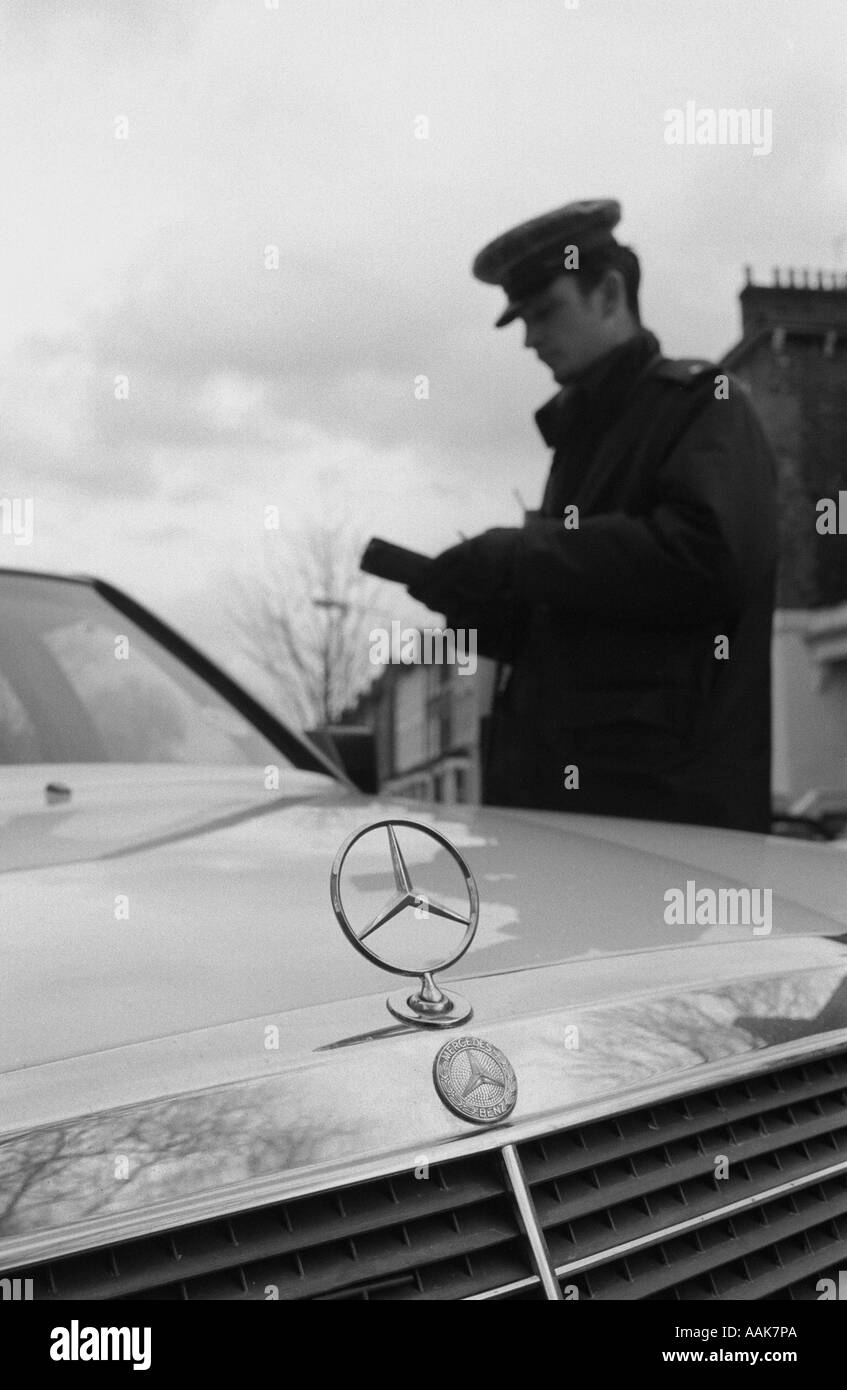 A traffic warden issuing a parking ticket to the owner of a Mercedes car, Hackney, London, UK, January 1995. Stock Photo