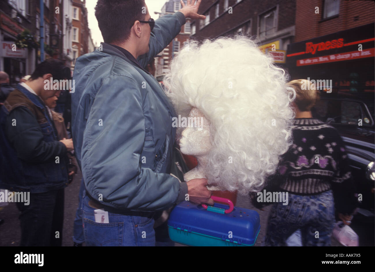 A drag queen out of costume holding his wig hails a taxi at the end of the Soho festival, Old Compton Street, London, UK. Stock Photo