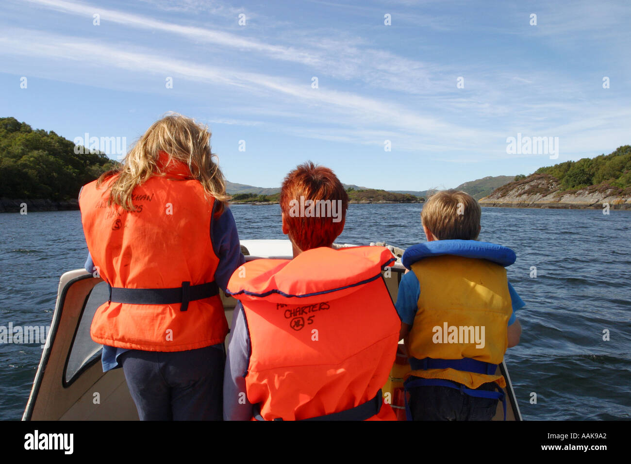 Family boating on a motor boat on a Scottish Loch Sunart in summer wearing safety gear Stock Photo