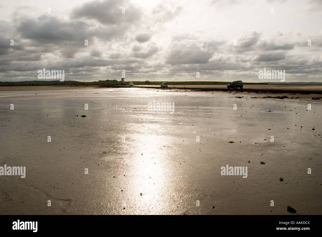 Vehicles crossing the causeway at low tide to the Holy Island of Lindisfarne, Northumberland. Stock Photo