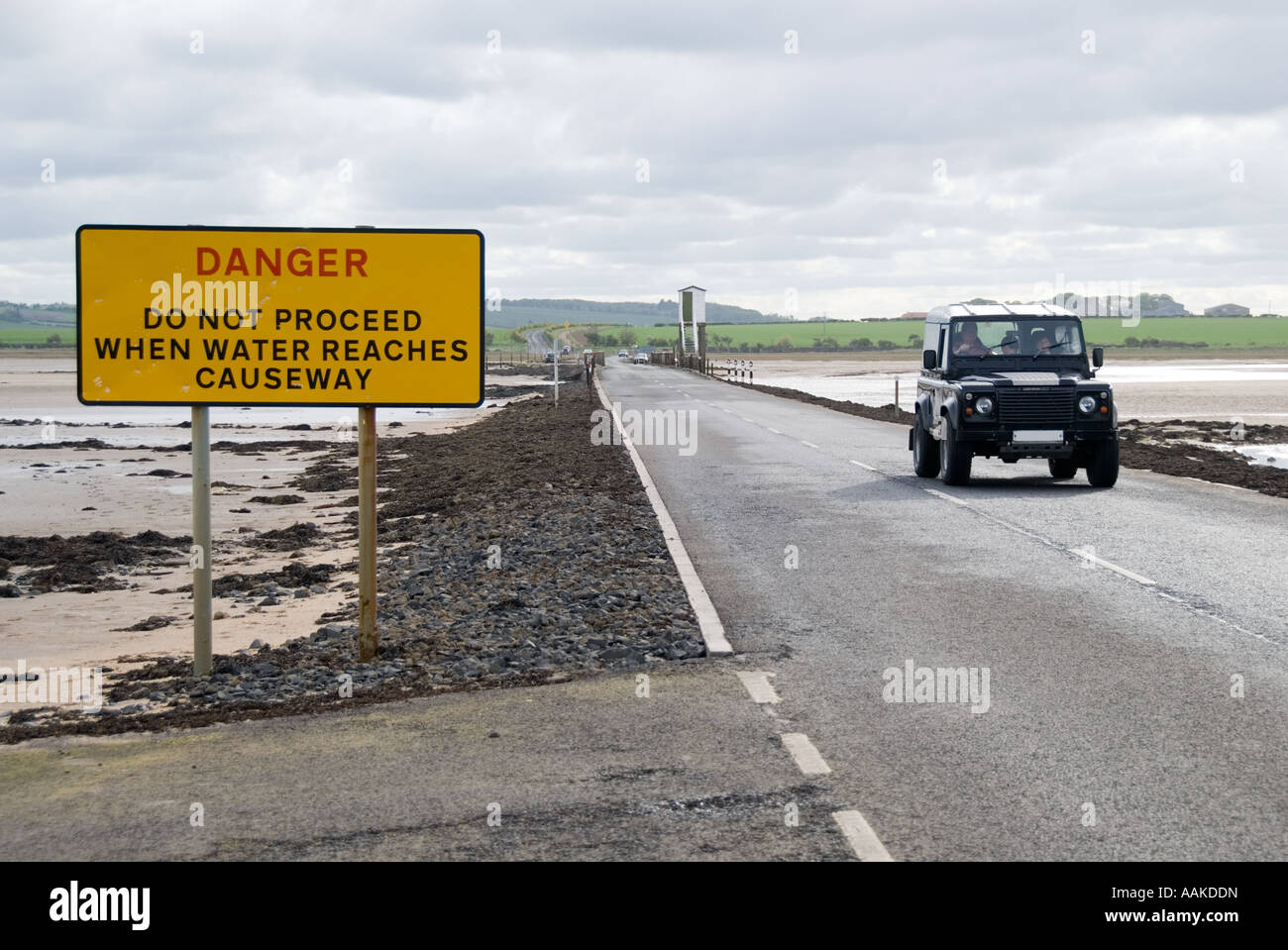 Vehicle crossing the causeway at low tide to the Holy Island of Lindisfarne, Northumberland. Stock Photo