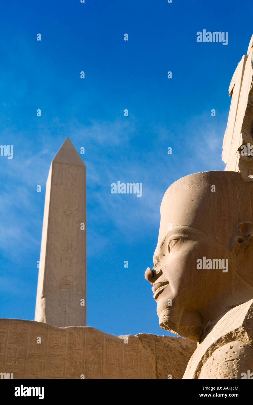 Statue of Ramses II with an obelisk in the background in Karnak Temple ...