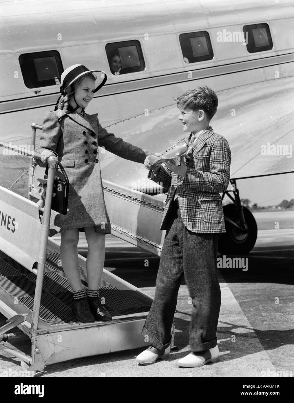 1940s BOY GIRL WALKING OFF BOARDING RAMP OF AIRPLANE BOY HOLDS TOY PLANE DRESS FASHION SUIT TIE Stock Photo