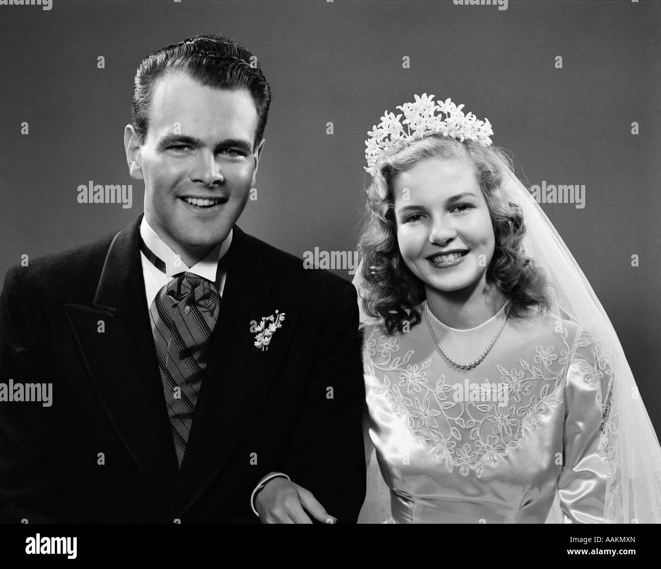 1940s PORTRAIT OF BRIDE AND GROOM LINKED ARM IN ARM LOOKING AT CAMERA Stock Photo